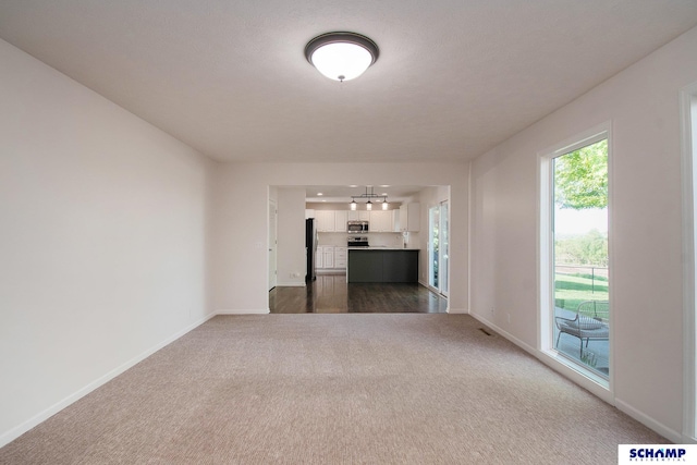 unfurnished living room with dark carpet, baseboards, and a chandelier