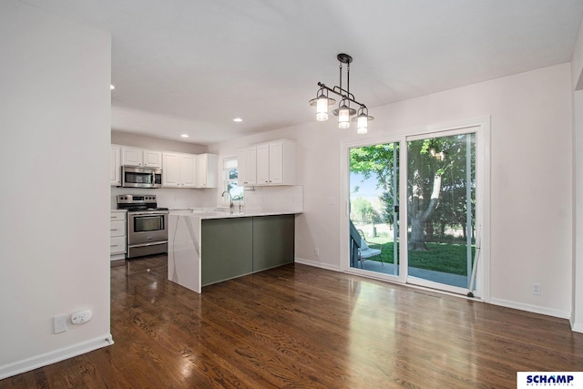 kitchen with appliances with stainless steel finishes, a sink, white cabinetry, a peninsula, and dark wood-type flooring