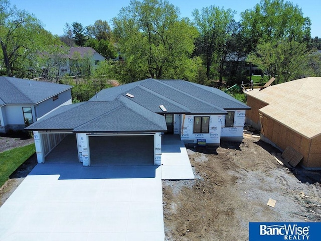 ranch-style house with concrete driveway, a shingled roof, and a garage