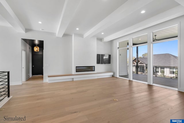 unfurnished living room featuring light wood-type flooring, baseboards, beamed ceiling, a glass covered fireplace, and recessed lighting