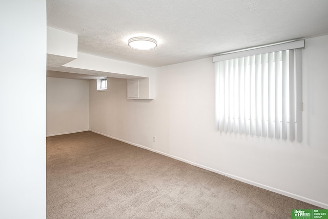 basement featuring baseboards, a textured ceiling, and carpet