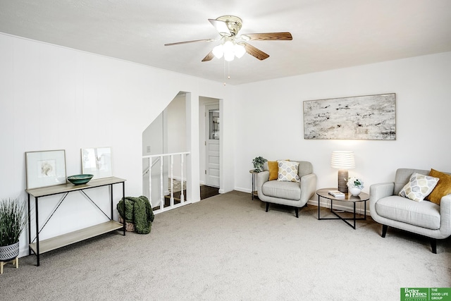 living area with a ceiling fan, carpet flooring, and an upstairs landing