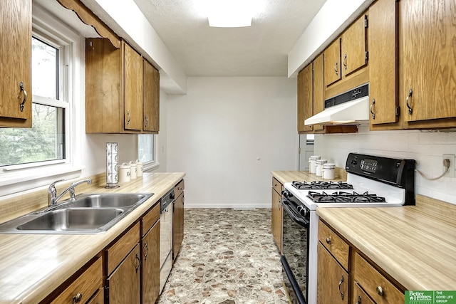 kitchen featuring backsplash, gas range, a sink, light countertops, and under cabinet range hood