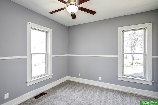 carpeted empty room featuring ceiling fan, visible vents, and baseboards
