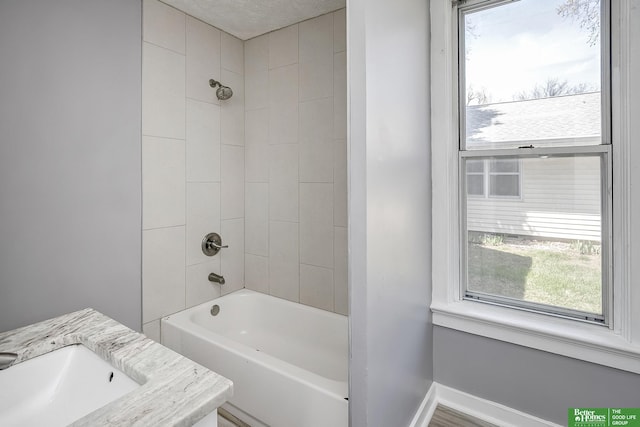 bathroom with a sink, washtub / shower combination, and a healthy amount of sunlight