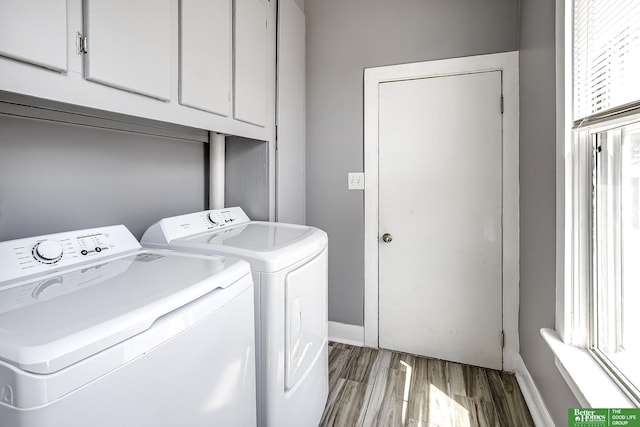 clothes washing area with baseboards, cabinet space, wood finished floors, and washing machine and clothes dryer