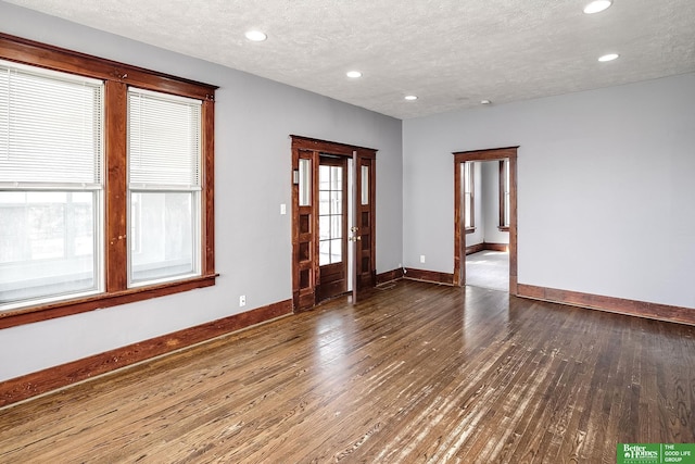 spare room with baseboards, recessed lighting, a textured ceiling, and wood finished floors