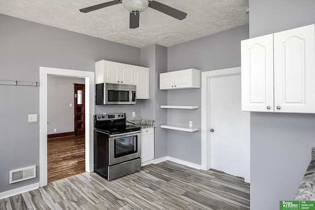 kitchen with light wood finished floors, a textured ceiling, stainless steel appliances, a ceiling fan, and visible vents