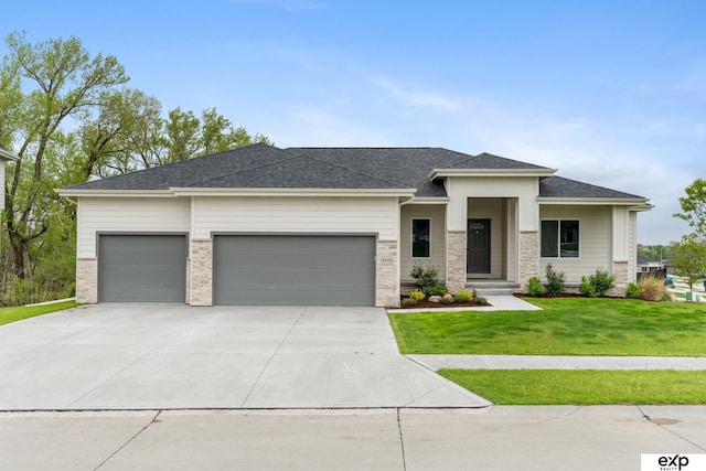 prairie-style house featuring concrete driveway, an attached garage, roof with shingles, and a front lawn