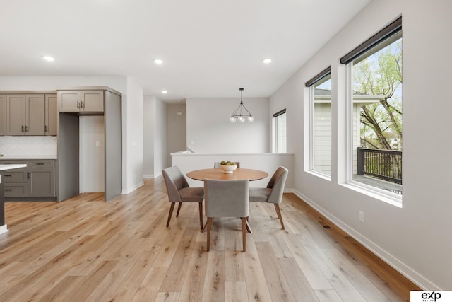 dining space with recessed lighting, baseboards, a notable chandelier, and light wood-type flooring