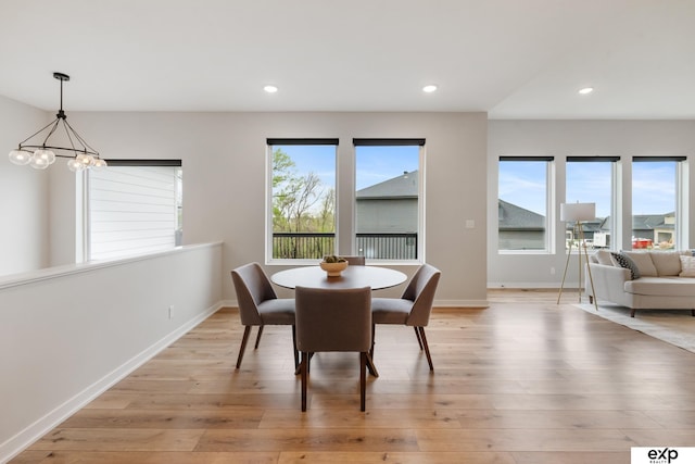 dining area with baseboards, light wood-style flooring, a chandelier, and a wealth of natural light