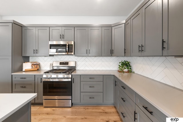 kitchen featuring light countertops, gray cabinets, appliances with stainless steel finishes, and light wood finished floors