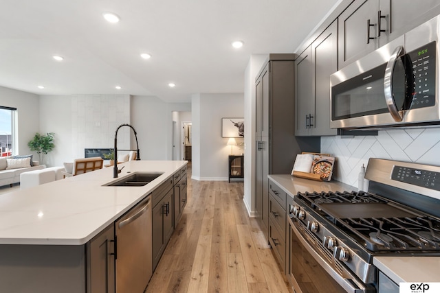 kitchen with light wood-type flooring, a sink, tasteful backsplash, and stainless steel appliances
