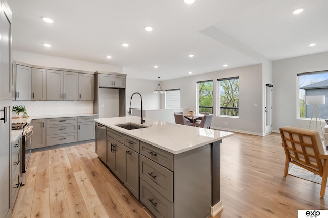 kitchen with light wood-style floors, a sink, gray cabinetry, and stainless steel appliances