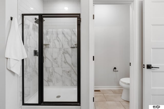 bathroom with baseboards, tile patterned flooring, a stall shower, and toilet