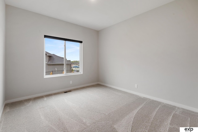 carpeted spare room featuring baseboards and visible vents