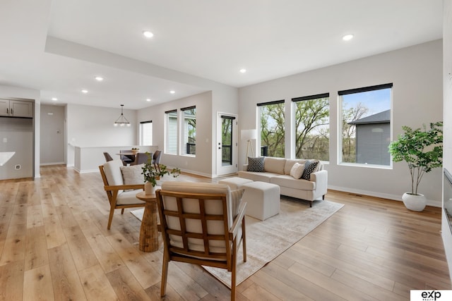 living room with recessed lighting, baseboards, a notable chandelier, and light wood-style floors