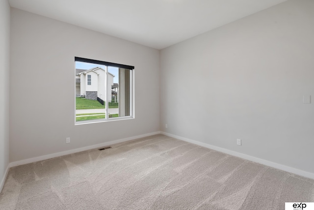 carpeted empty room with visible vents and baseboards