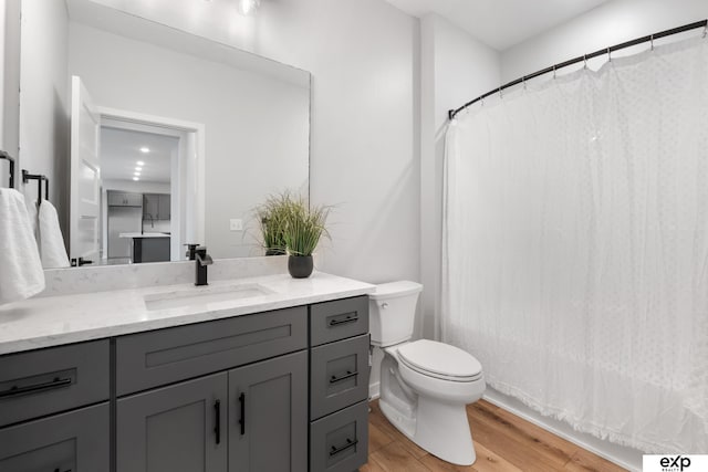 bathroom featuring vanity, wood finished floors, toilet, and curtained shower