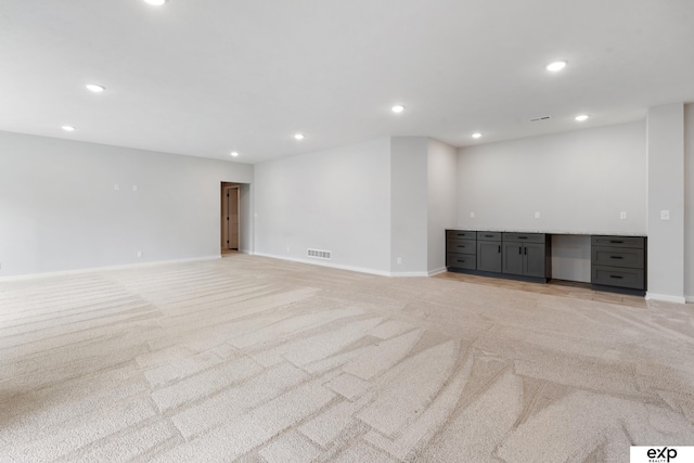 basement with baseboards, light colored carpet, recessed lighting, and visible vents