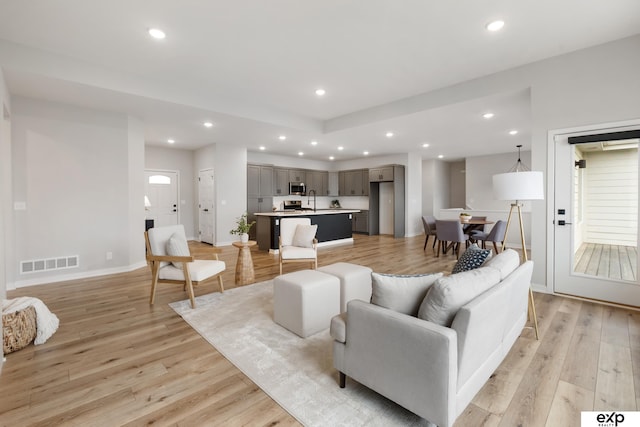 living area with light wood-style floors, baseboards, recessed lighting, and visible vents