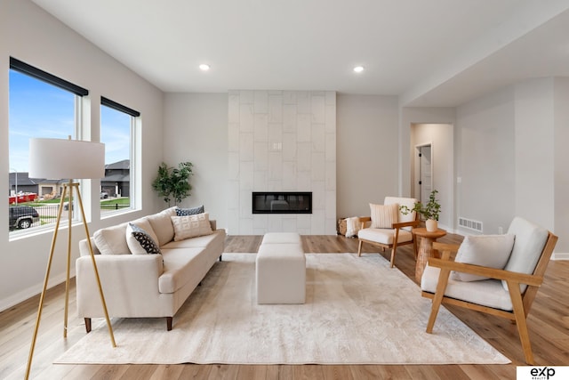 living area featuring visible vents, a fireplace, baseboards, recessed lighting, and light wood-style flooring