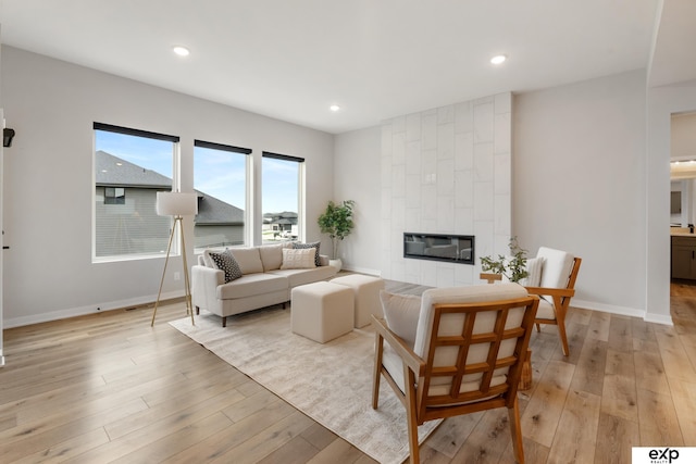 living area featuring a fireplace, recessed lighting, baseboards, and light wood-type flooring