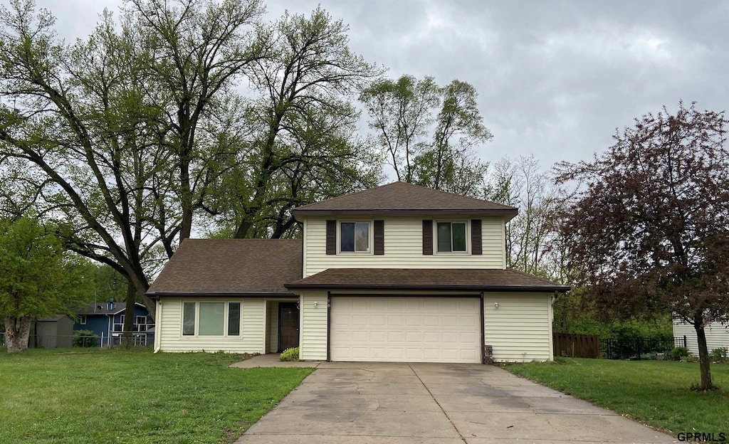 traditional-style home featuring a garage, fence, driveway, and a front yard