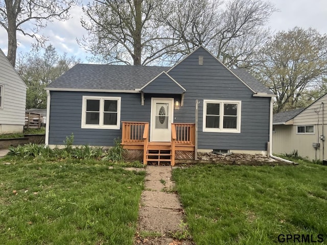 rear view of property with a yard, a deck, and a shingled roof