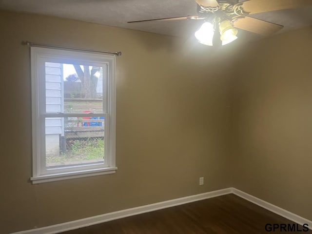 empty room with baseboards, ceiling fan, and dark wood-style flooring