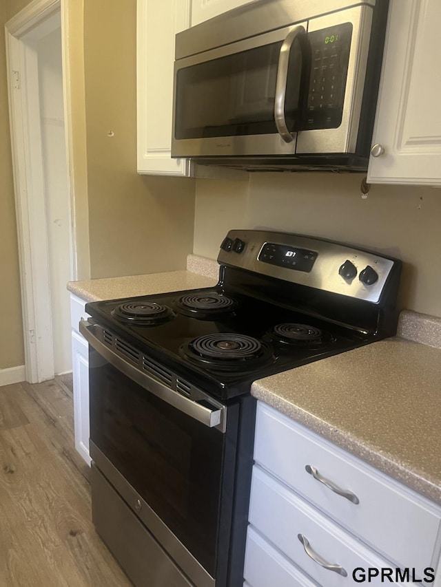 kitchen featuring light countertops, stainless steel appliances, white cabinetry, and light wood-type flooring