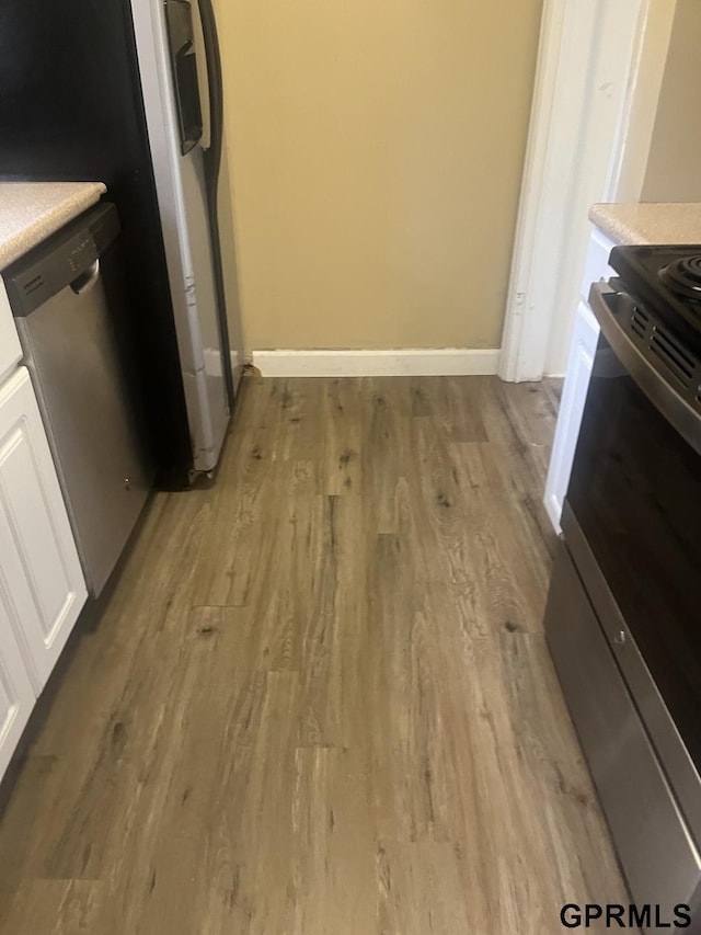 details with light wood-type flooring, light countertops, baseboards, stainless steel appliances, and white cabinetry