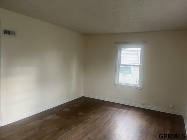 unfurnished room with baseboards, visible vents, and dark wood-style floors