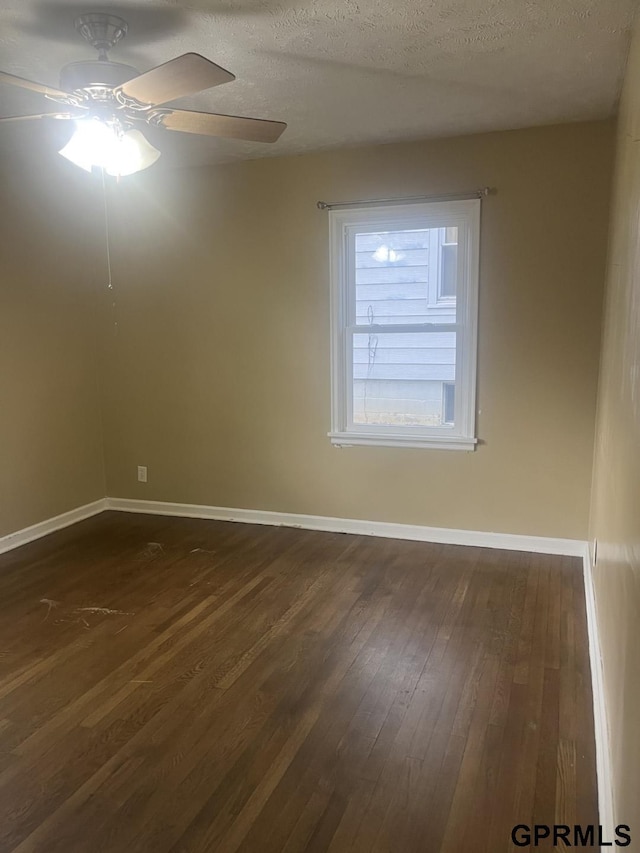 empty room with baseboards, a ceiling fan, dark wood-style flooring, and a textured ceiling