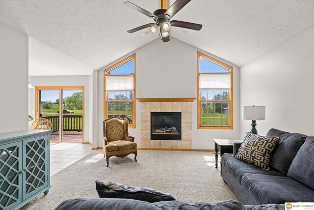 554 Shawnee Blvd, Tecumseh, NE 68450 - carpeted living room with ceiling fan, a tiled fireplace, vaulted ceiling, a textured ceiling, and baseboards