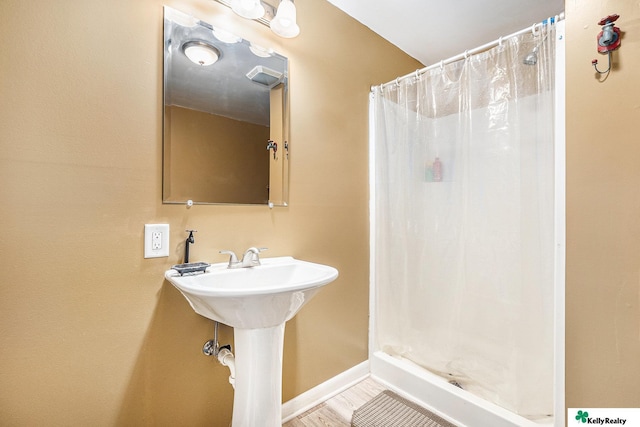 bathroom with baseboards, a sink, and a stall shower