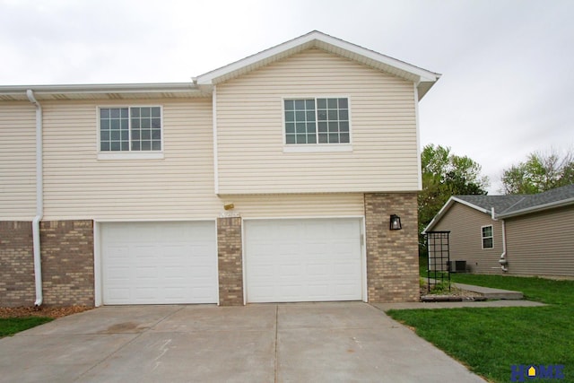 5203 N 9th Cir, Lincoln, NE 68521 - view of front of home featuring cooling unit, an attached garage, concrete driveway, and brick siding