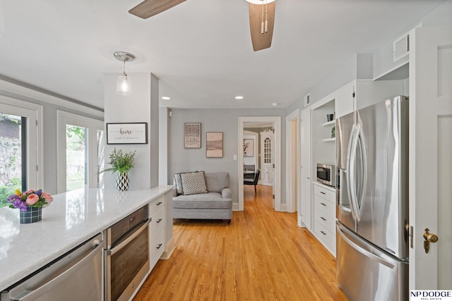 kitchen featuring light countertops, stainless steel appliances, a ceiling fan, and white cabinetry
