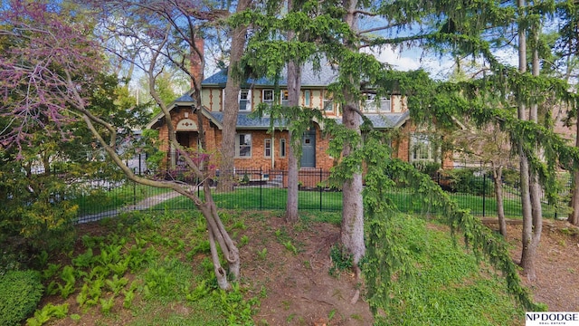 view of front of home with fence private yard, brick siding, and a chimney