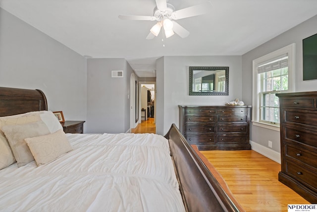 bedroom with baseboards, a ceiling fan, wood finished floors, and visible vents