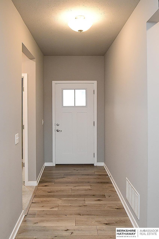 7911 N 149th St, Bennington, NE 68007 - doorway with a textured ceiling, baseboards, light wood-type flooring, and visible vents