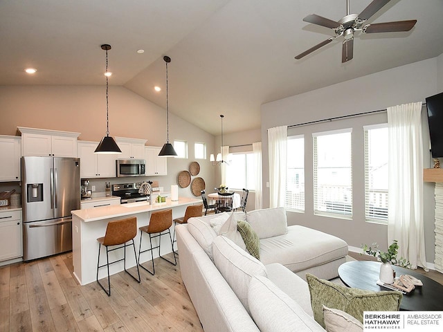 7911 N 149th St, Bennington, NE 68007 - living area featuring light wood-style flooring, high vaulted ceiling, and ceiling fan with notable chandelier