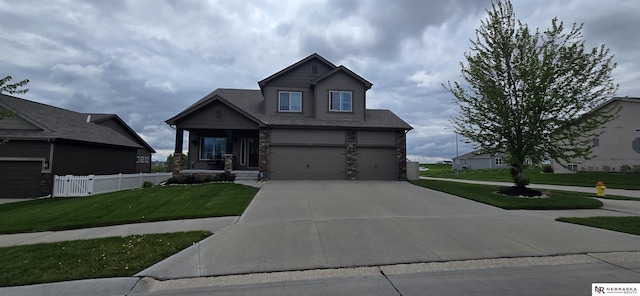 craftsman house with fence, stone siding, a garage, a front yard, and concrete driveway