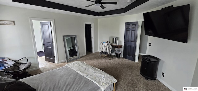 carpeted bedroom featuring baseboards and a raised ceiling