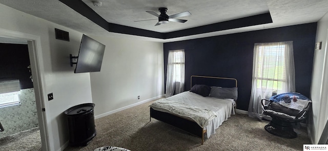 bedroom featuring multiple windows, a raised ceiling, carpet, baseboards, and visible vents