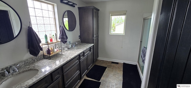full bathroom featuring baseboards, a sink, walk in shower, and double vanity