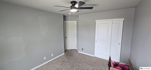 unfurnished bedroom with baseboards, a ceiling fan, carpet, and a closet