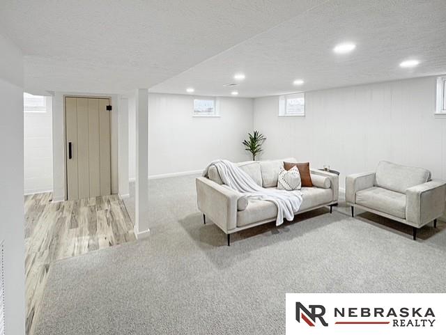 1816 S 49th St, Lincoln, NE 68506 - carpeted living room featuring baseboards, recessed lighting, a textured ceiling, and wood finished floors