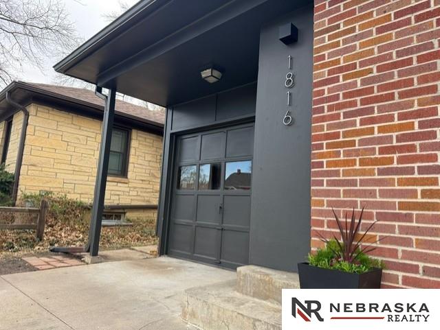 1816 S 49th St, Lincoln, NE 68506 - entrance to property featuring a garage, driveway, and brick siding