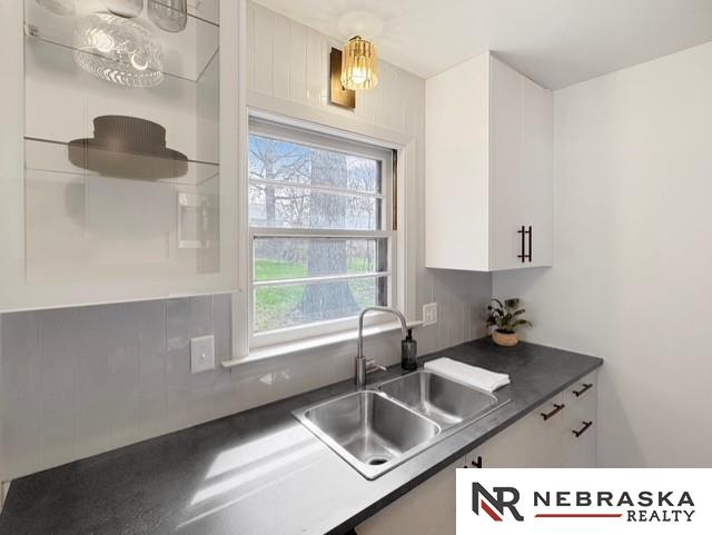 1816 S 49th St, Lincoln, NE 68506 - kitchen featuring white cabinetry, dark countertops, and a sink